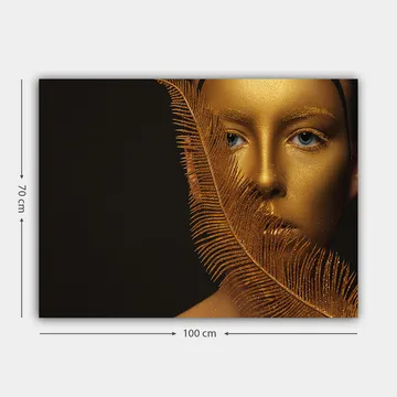 Canvastavla 70x100 cm - Ansiktsporträtt med en gyllene yta och blå ögon, omgiven av en dekorativ fjäderliknande struktur - Guld / Blå - Inredning - Tavlor & posters - Canvastavla
