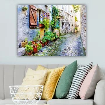 Canvastavla 70x100 cm - Charmig gränd med stenhus och blomsterkrukor som skapar en livlig atmosfär - Grön / Blå / Beige - Inredning - Tavlor & posters - Canvastavla