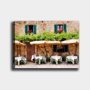 Canvastavla 70x100 cm - Charmig uteservering med vita bord och gröna dukar framför en gammal stenbyggnad med fönsterluckor i mörkgrön färg - Mörkgrön / Vit / Tegelröd - Inredning - Tavlor & posters - Canvastavla