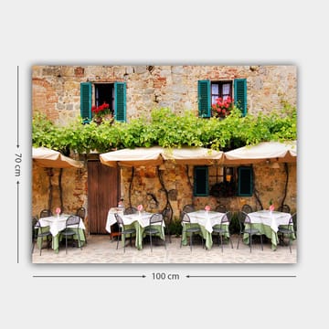 Canvastavla 70x100 cm - Charmig uteservering med vita bord och gröna dukar framför en gammal stenbyggnad med fönsterluckor i mörkgrön färg - Mörkgrön / Vit / Tegelröd - Inredning - Tavlor & posters - Canvastavla