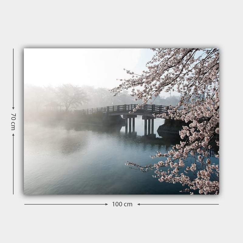 Canvastavla 70x100 cm - Dimmig scen med en bro som sträcker sig över en stilla sjö, omgiven av körsbärsträd i blom - Ljusrosa / Blå / Grå - Inredning - Tavlor & posters - Canvastavla