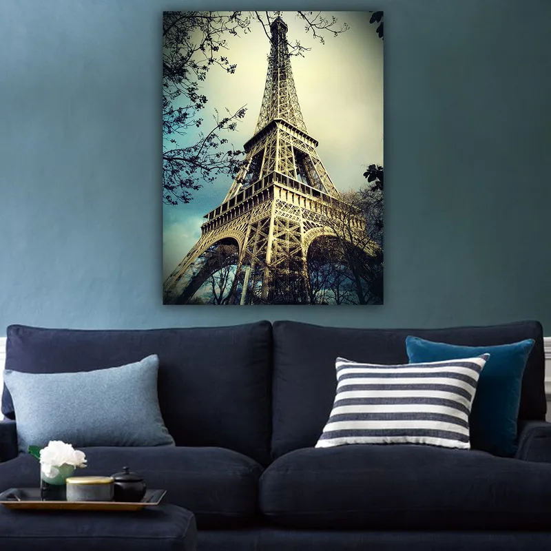 Canvastavla 70x100 cm - Eiffeltornet i Paris, fångat från en låg vinkel med omgivande trädgrenar - Grå / Beige / Blå - Inredning - Tavlor & posters - Canvastavla