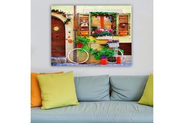 Canvastavla 70x100 cm - Färgglad cykel prydd med blommor och krukor framför en charmig vägg med fönster och dekorationer - Grön / Rosa / Orange - Inredning - Tavlor & posters - Canvastavla