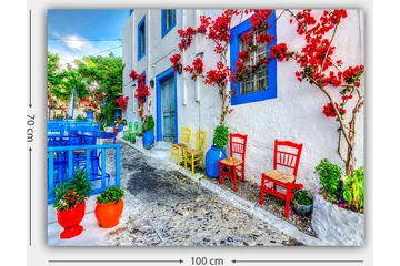 Canvastavla 70x100 cm - Färgglad gata med blommor och stolar i olika färger som skapar en livlig atmosfär - Blå / Röd / Grön - Inredning - Tavlor & posters - Canvastavla