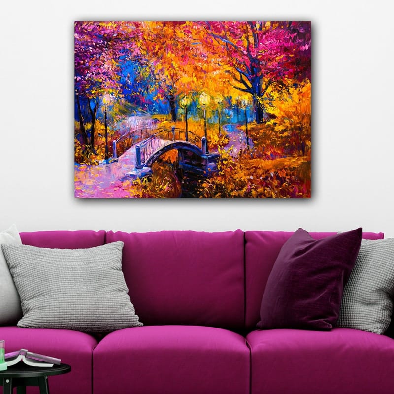 Canvastavla 70x100 cm - Färgsprakande höstscen med en bro som sträcker sig över en stilla vattenyta, omgiven av träd i varma höstfärger - Orange / Lila / Gult - Inredning - Tavlor & posters - Canvastavla