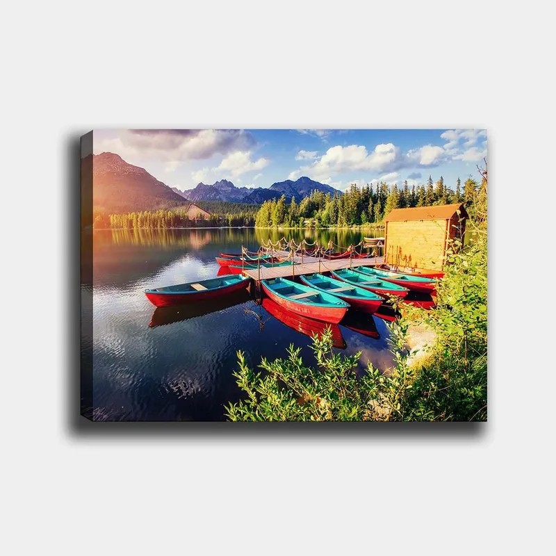 Canvastavla 70x100 cm - Flera färgglada båtar ligger vid en spegelblanka sjö omgiven av grönskande träd och berg, Röd / Turkos / Grön