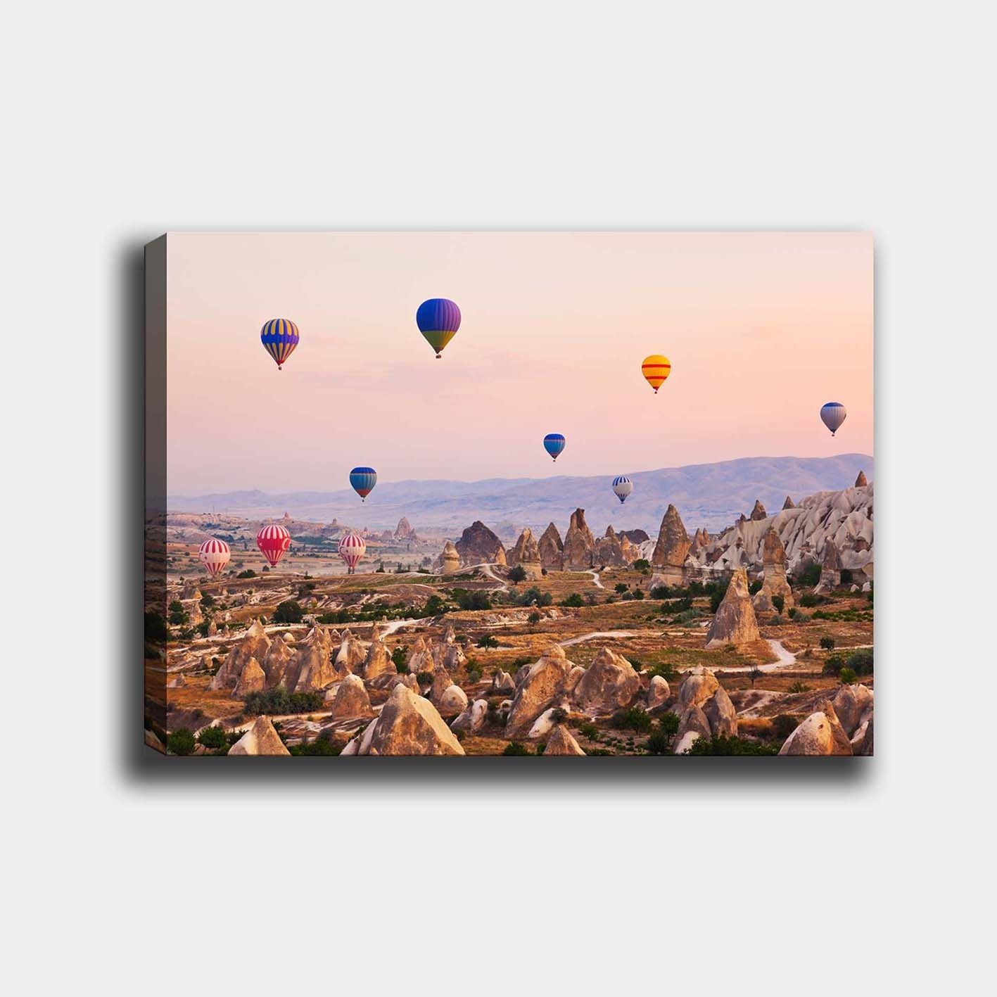 Canvastavla 70x100 cm - Flera färgglada luftballonger sväva över en dramatisk landskap med unika klippformationer - Blå / Röd / Orange