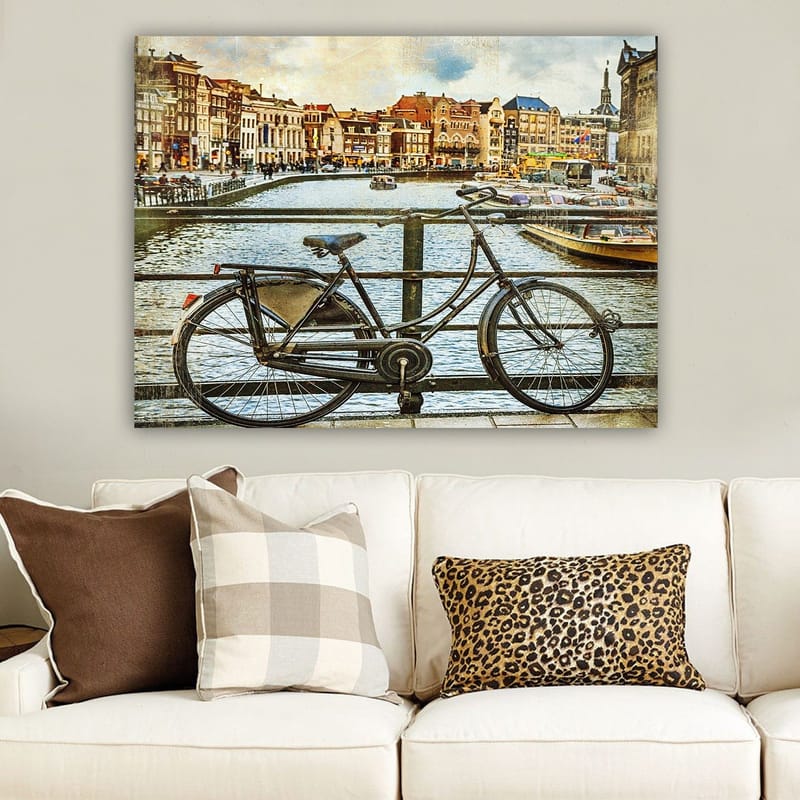 Canvastavla 70x100 cm - Gammal cykel som står lutad mot en räcke vid en kanal med pittoreska byggnader i bakgrunden - Svart / Grå / Brun - Inredning - Tavlor & posters - Canvastavla