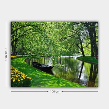 Canvastavla 70x100 cm - Idyllisk sjöscen med en båt som ligger stilla vid en grönskande strand omgiven av träd och blommor - Grön / Svart / Gul - Inredning - Tavlor & posters - Canvastavla
