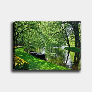 Canvastavla 70x100 cm - Idyllisk sjöscen med en båt som ligger stilla vid en grönskande strand omgiven av träd och blommor - Grön / Svart / Gul - Inredning - Tavlor & posters - Canvastavla