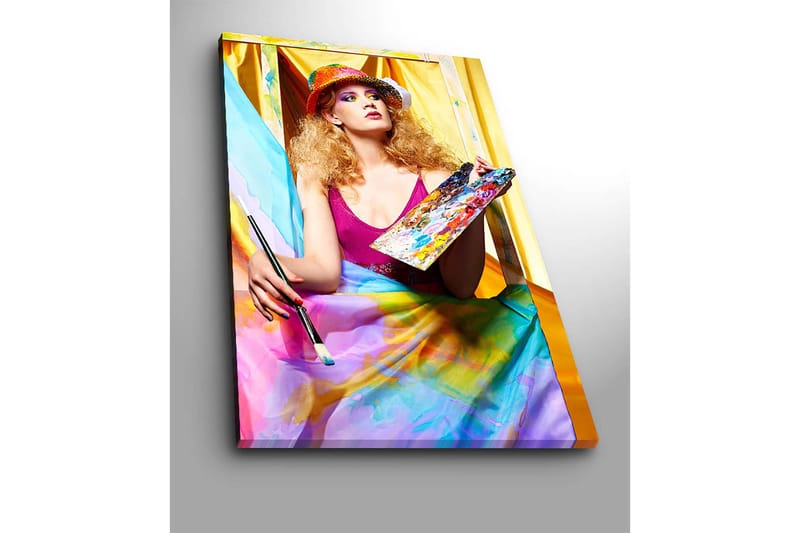 Canvastavla 70x100 cm - Kreativ kvinna som målar med en palett i handen, omgiven av färgglada tyger - Rosa / Blå / Gul - Inredning - Tavlor & posters - Canvastavla