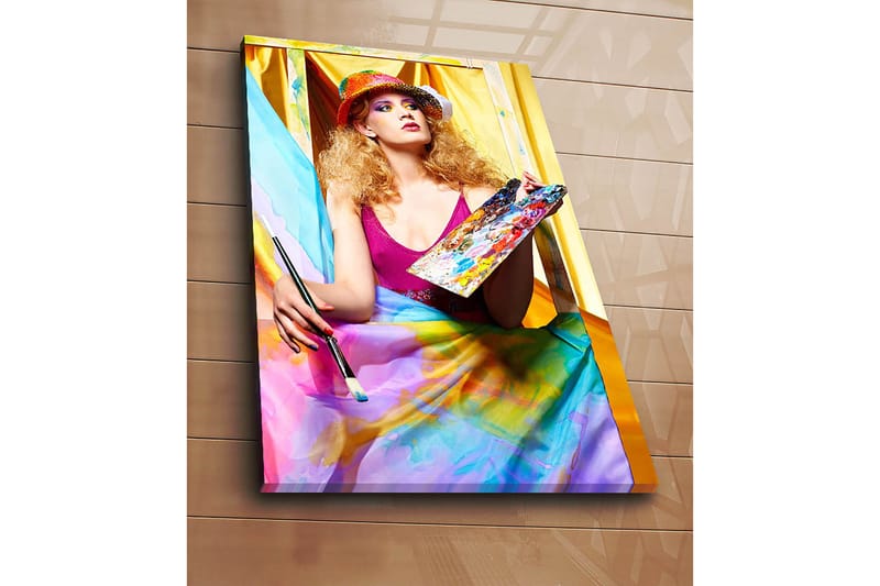 Canvastavla 70x100 cm - Kreativ kvinna som målar med en palett i handen, omgiven av färgglada tyger - Rosa / Blå / Gul - Inredning - Tavlor & posters - Canvastavla