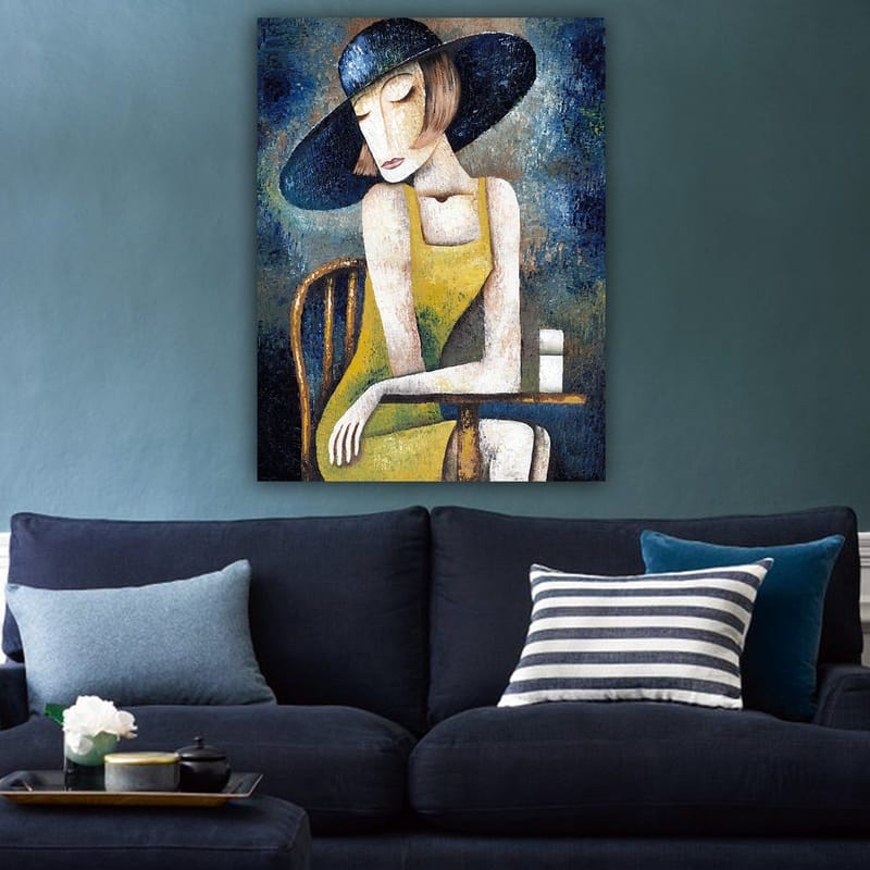 Canvastavla 70x100 cm - Kvinna i en gul klänning sitter vid ett bord med en vit kopp, iförd en stor svart hatt - Gul / Svart / Blågrön - Inredning - Tavlor & posters - Canvastavla