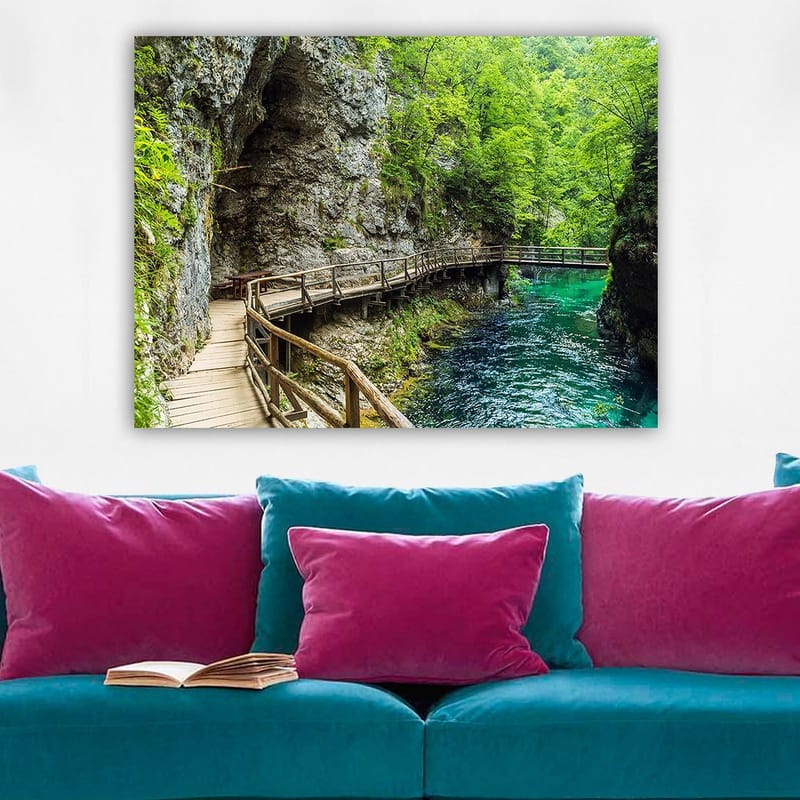 Canvastavla 70x100 cm - Naturskön vy av en träbro som slingrar sig genom en grönskande ravin vid en klar, turkos flod - Grön / Turkos / Grå - Inredning - Tavlor & posters - Canvastavla