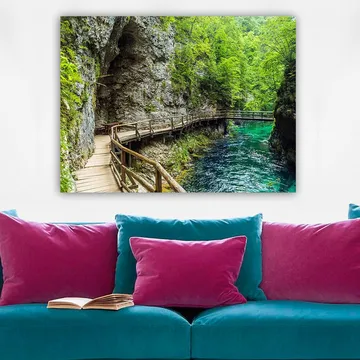 Canvastavla 70x100 cm - Naturskön vy av en träbro som slingrar sig genom en grönskande ravin vid en klar, turkos flod - Grön / Turkos / Grå - Inredning - Tavlor & posters - Canvastavla
