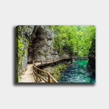 Canvastavla 70x100 cm - Naturskön vy av en träbro som slingrar sig genom en grönskande ravin vid en klar, turkos flod - Grön / Turkos / Grå - Inredning - Tavlor & posters - Canvastavla