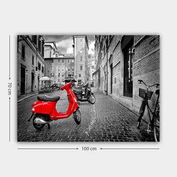Canvastavla 70x100 cm - Röd scooter står i en svartvit stadsmiljö med kullerstensgator och byggnader - Röd / Svart / Grå - Inredning - Tavlor & posters - Canvastavla