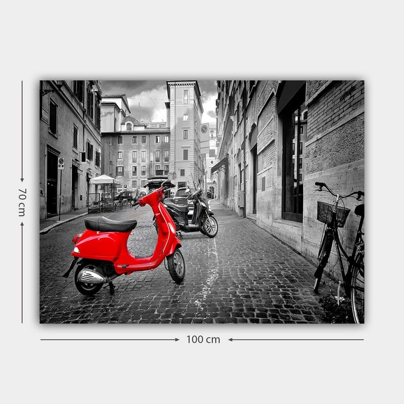 Canvastavla 70x100 cm - Röd scooter står i en svartvit stadsmiljö med kullerstensgator och byggnader - Röd / Svart / Grå - Inredning - Tavlor & posters - Canvastavla