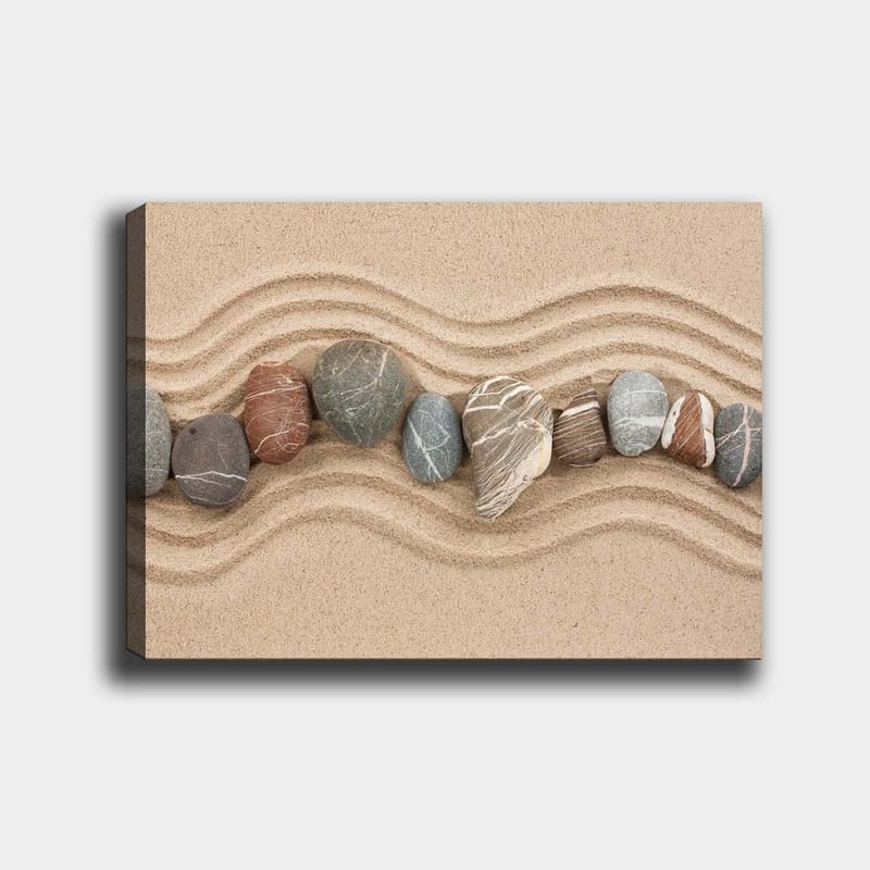 Canvastavla 70x100 cm - Rad av släta stenar placerade på en sandig yta med vågiga mönster, Sandbeige / Grå / Rödbrun