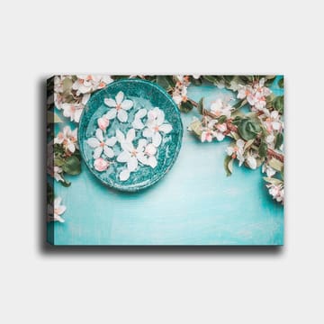 Canvastavla 70x100 cm - Skål med blommor omgiven av grönskande kvistar och blommor på en ljusblå bakgrund - Turkos / Vit / Rosa - Inredning - Tavlor & posters - Canvastavla