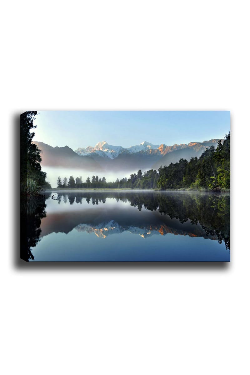 Canvastavla 70x100 cm - Spegelbild av majestätiska berg som reflekteras i en stilla sjö omgiven av grönskande skog, Blå / Grön / Vit