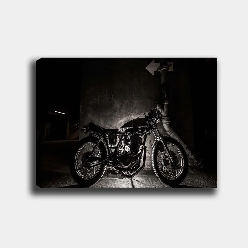 Canvastavla 70x100 cm - Stilren motorcykel i en urban miljö med fokus på detaljer och skuggor, Svart / Grå