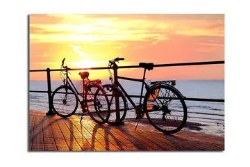 Canvastavla 70x100 cm - Två cyklar som står på en brygga vid solnedgången över havet - Orange / Svart / Gult - Inredning - Tavlor & posters - Canvastavla