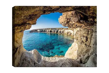 Canvastavla 70x100 cm - Utsikt genom en klippöppning mot en klarblå havsstrand - Blå / Beige / Vit - Inredning - Tavlor & posters - Canvastavla