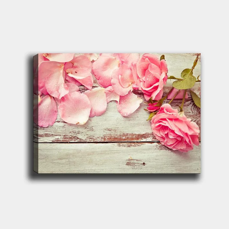 Canvastavla 70x100 cm - Vacker komposition av rosa rosor och rosblad på en träyta, Rosa / Grön / Brun