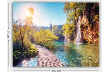 Canvastavla 70x100 cm - Vacker naturvy med en träbro som leder genom grönskande landskap och en vattenfall i bakgrunden - Grön / Blå / Gul - Inredning - Tavlor & posters - Canvastavla