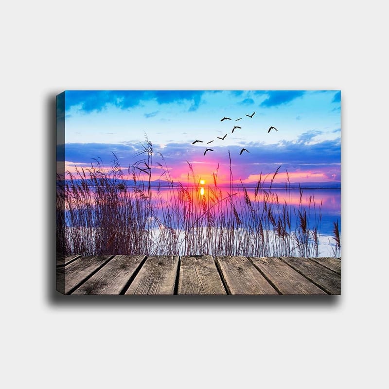 Canvastavla 70x100 cm - Vacker solnedgång över en spegelblanka sjö med fåglar som flyger över vattnet, Blå / Orange / Lila