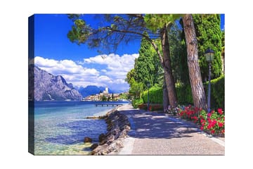 Canvastavla 70x100 cm - Vacker strandpromenad med träd och blommor vid en sjö, omgiven av berg och en pittoresk stad i bakgrunden - Blå / Grön / Röd - Inredning - Tavlor & posters - Canvastavla
