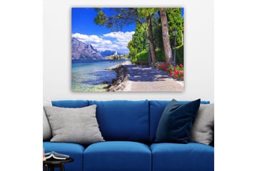 Canvastavla 70x100 cm - Vacker strandpromenad med träd och blommor vid en sjö, omgiven av berg och en pittoresk stad i bakgrunden - Blå / Grön / Röd - Inredning - Tavlor & posters - Canvastavla