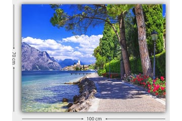 Canvastavla 70x100 cm - Vacker strandpromenad med träd och blommor vid en sjö, omgiven av berg och en pittoresk stad i bakgrunden - Blå / Grön / Röd - Inredning - Tavlor & posters - Canvastavla