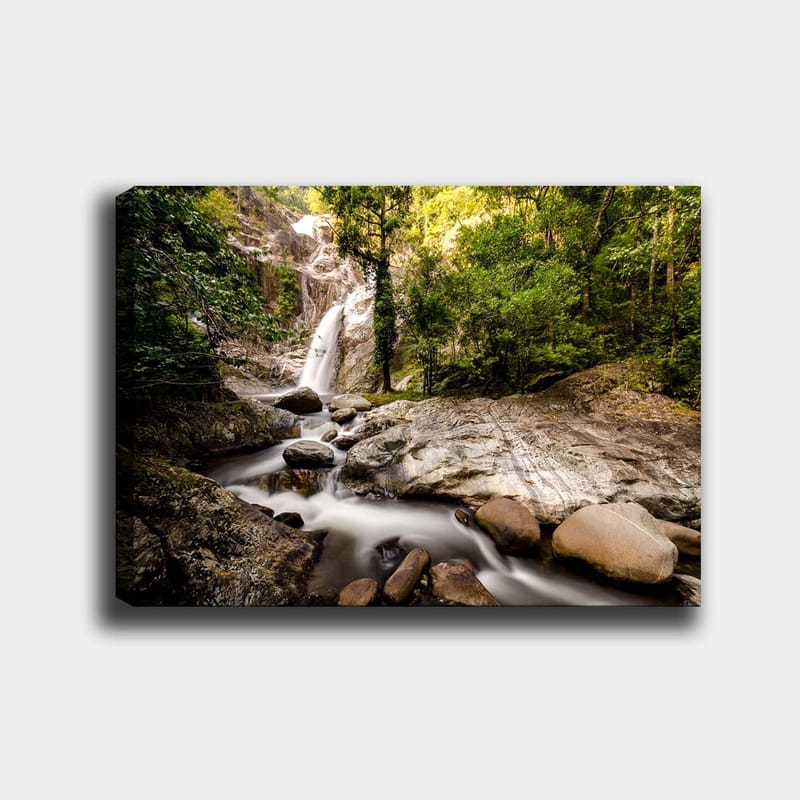 Canvastavla 70x100 cm - Vacker vattenfallsscen omgiven av frodig grönska och klippblock, Grön / Grå / Brun