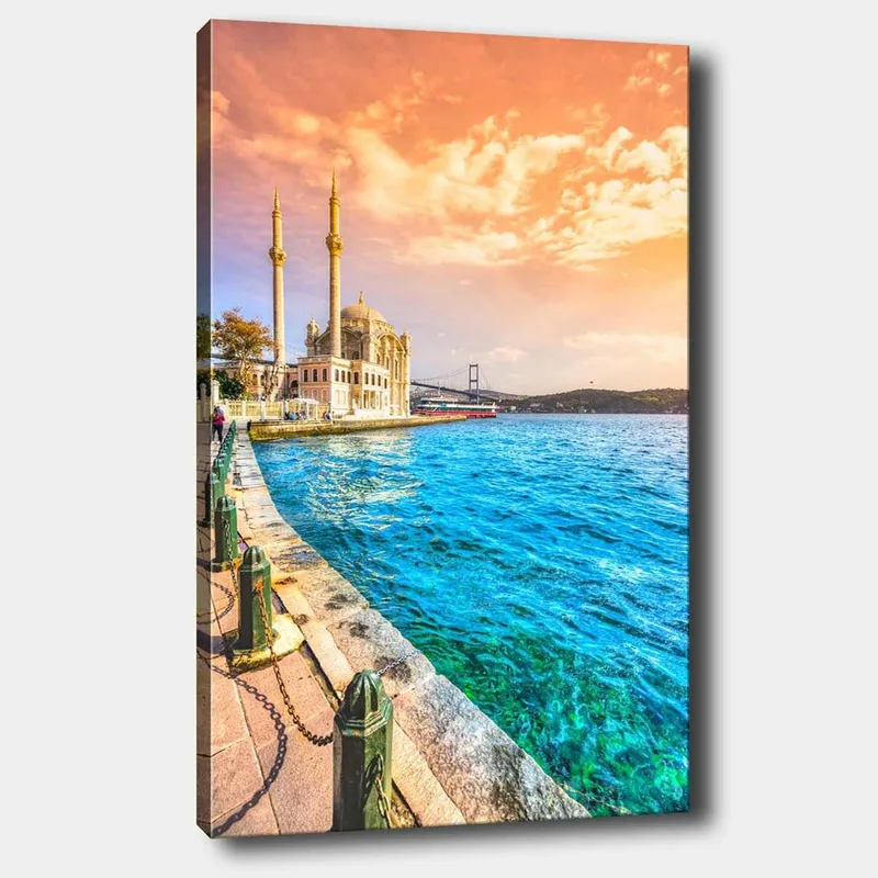 Canvastavla 70x100 cm - Vacker vy av en moské vid vattnet med en bro i bakgrunden under en färgsprakande himmel, Blå / Orange / Beige