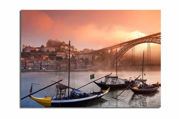 Canvastavla 70x100 cm - Vacker vy av floden med traditionella båtar och en majestätisk bro i bakgrunden, omgiven av färgglada hus - Orange / Blå / Gul - Inredning - Tavlor & posters - Canvastavla