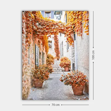 Canvastavla 70x100 cm - Pittoresk gränd omgiven av färgglada höstlöv och krukväxter - Orange / Brunt / Gult - Inredning - Tavlor & posters - Canvastavla
