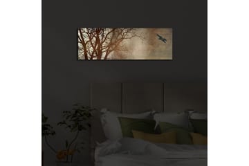 Canvastavla med LED-belysning 30x90 cm - Silhuett av träd med en fågel i flykt mot en mjukt tonad bakgrund - Mörkbrun / Beige / Svart - Inredning - Tavlor & posters - Canvastavla
