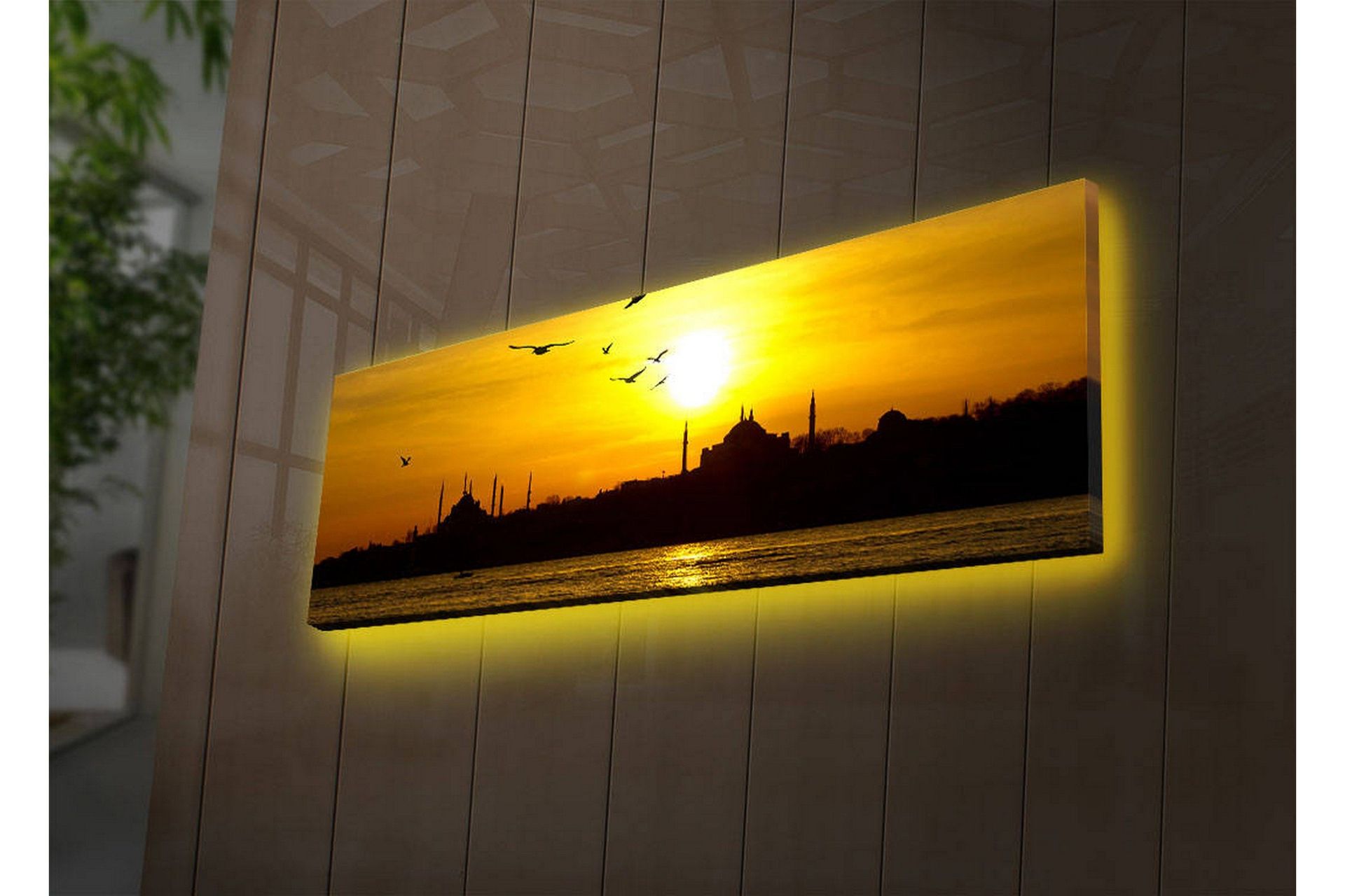 Canvastavla med LED-belysning 30x90 cm - Solnedgång över en stadssilhuett med fåglar i flykt - Guld / Svart / Orange