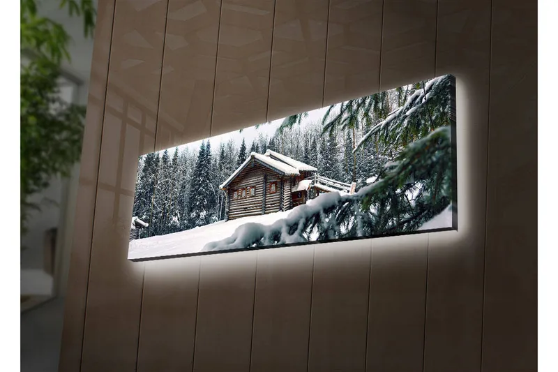 Canvastavla med LED-belysning 30x90 cm - Vinterlandskap med en stuga omgiven av snö och granar, Vit / Grön / Brun