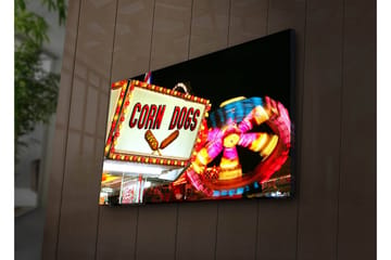 Canvastavla med LED-belysning 45x70 cm - Ljus och färgglad skylt med texten CORN DOGS och en snurrande karusell i bakgrunden - Röd / Gul / Blå - Inredning - Tavlor & posters - Canvastavla